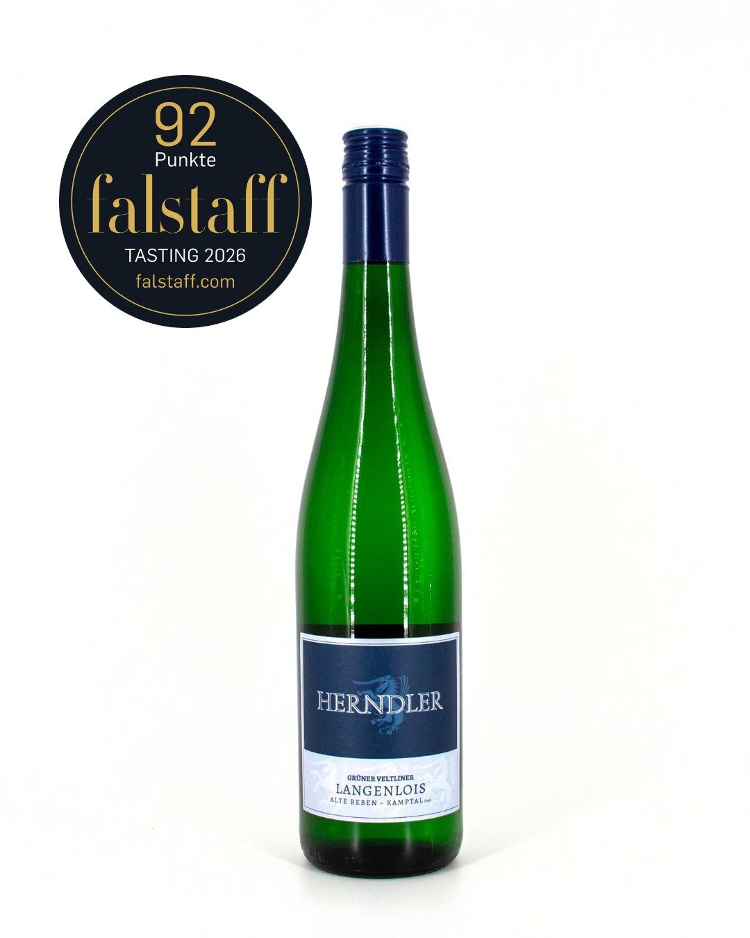 Green wine bottle with blue label 'HERNDLER' on white background; round black-gold Falstaff tasting badge ('92 Punkte', 2026) to the left.