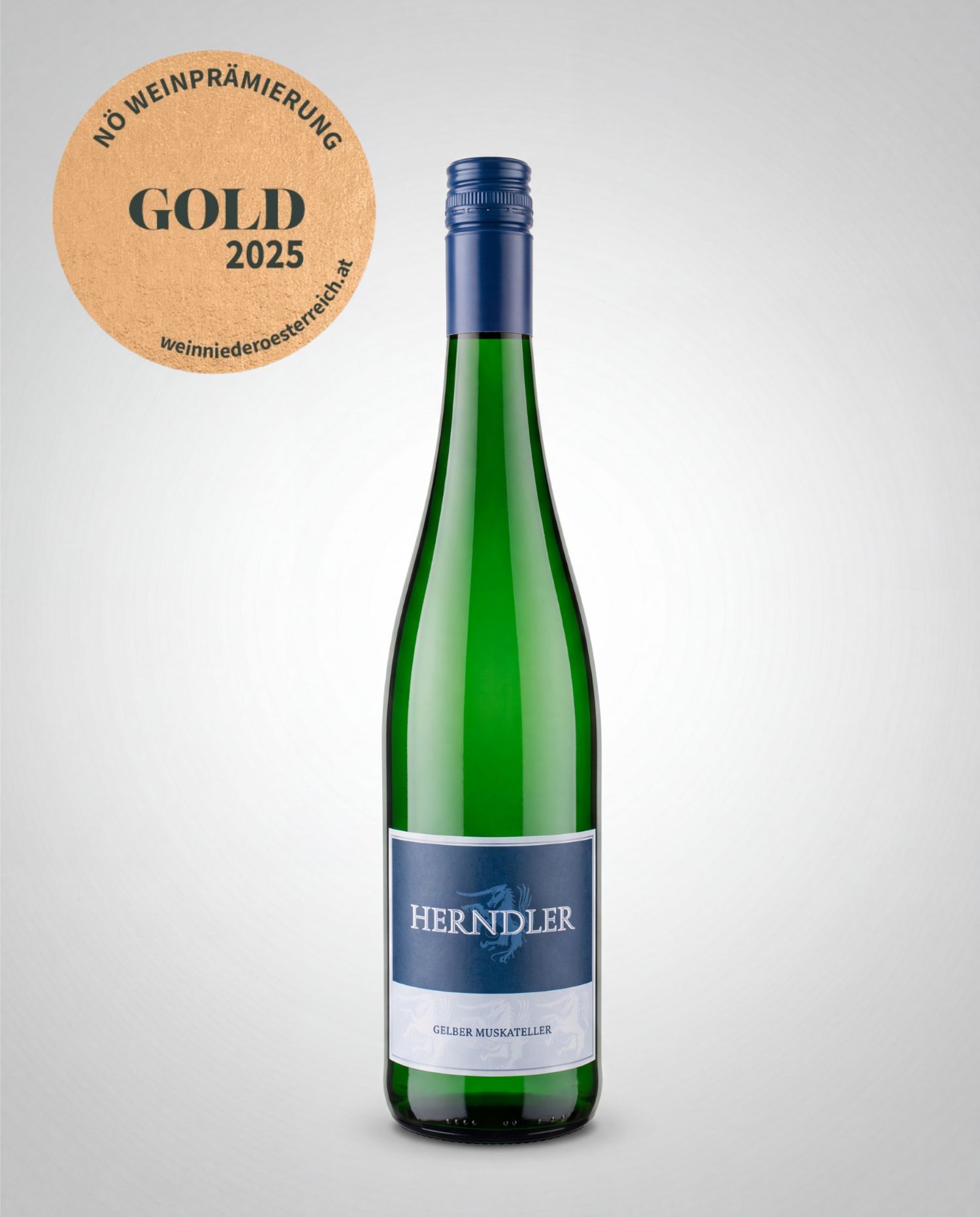 Gelber Muskateller Weingut Herndler Gold 2025 - Weingut Herndler Shop Green glass wine bottle with a blue neck foil and label reading HERNDLER Gelber Muskateller, placed upright against a light gradient background; a circular gold award seal sits to the left reading Gold 2025.