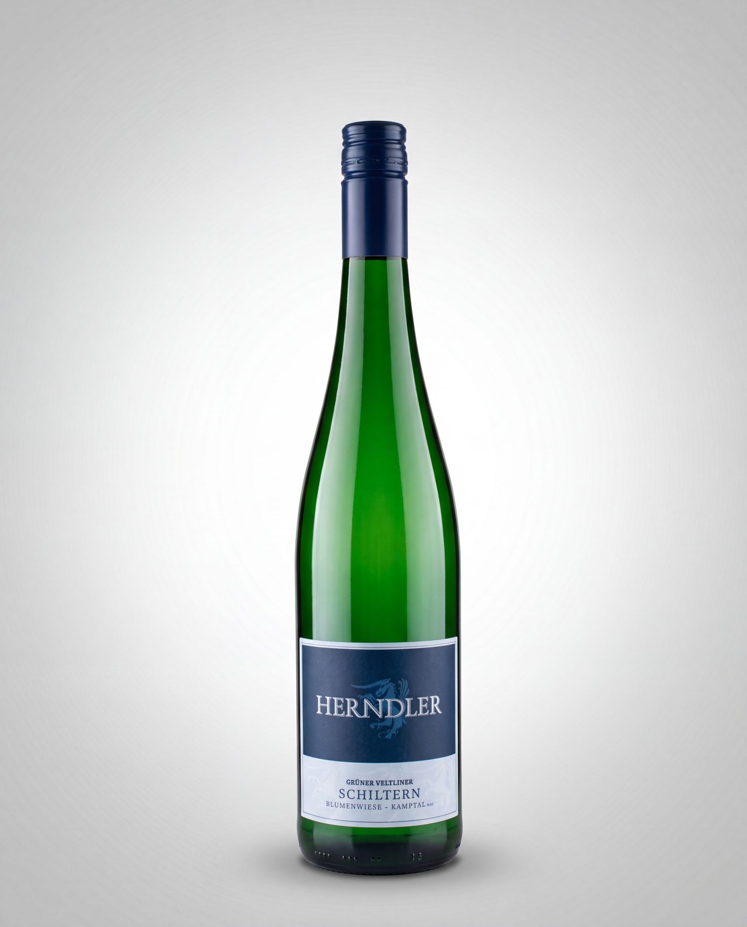 Grüner Veltliner Blumenwiese Weingut Herndler - Weingut Herndler Shop Green wine bottle with a blue capsule and a dark blue HERNDLER label on a light gradient background.