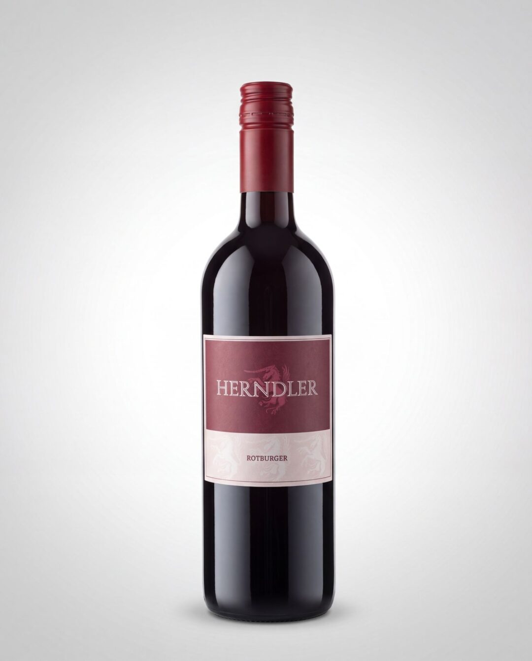 Full bottle of red wine with a maroon capsule and pink label reading 'HERNDLER' and 'ROTBURGER' against a light gradient background.