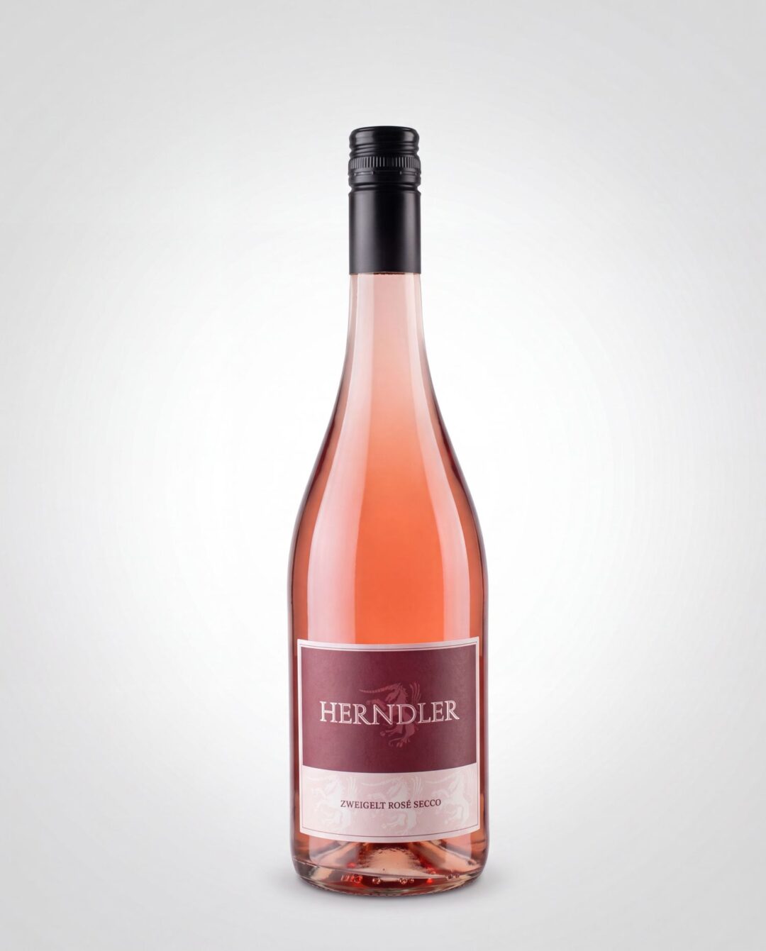 Rosé wine bottle with a black screw cap, pink liquid visible through the glass and a maroon label that reads 'HENDLER' (ZWEIGELT ROSÉ SECCO).
